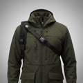 Bretelle harnais carabine noire portée en travers de la poitrine sur une veste softshell vert olive